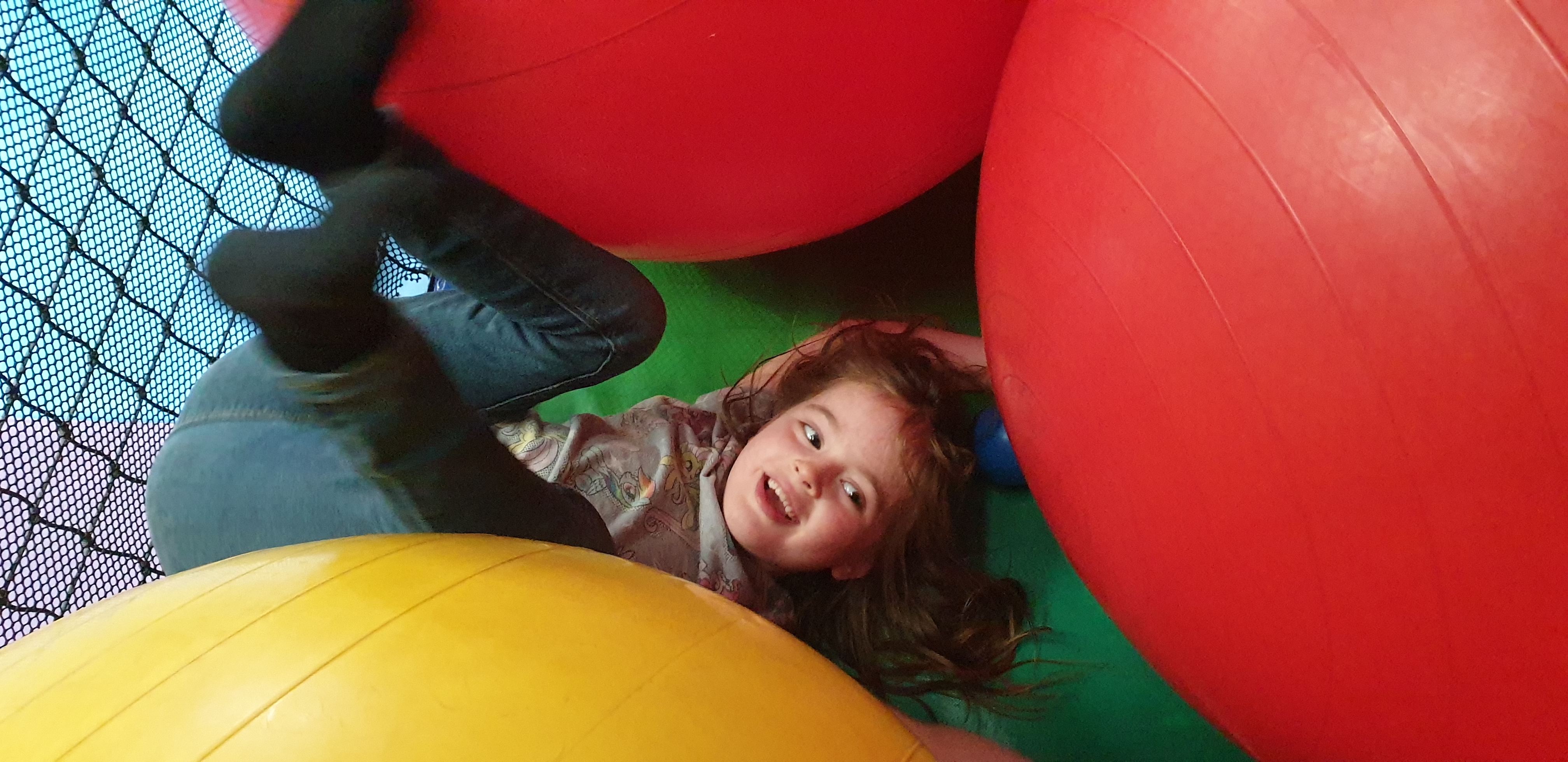 Full image of Annabel buried under giant balls.