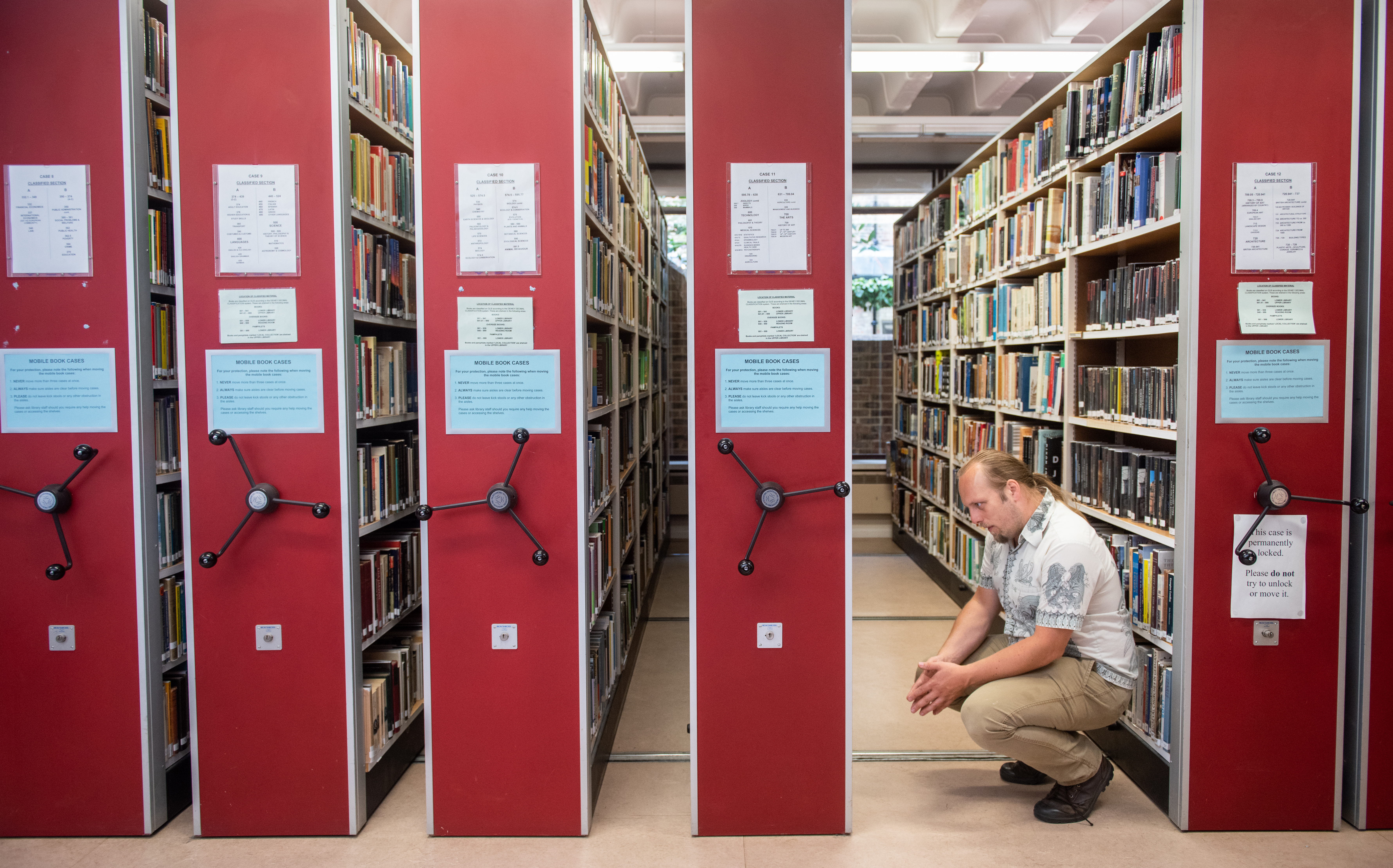 Full image of Dan looks at a low shelf.