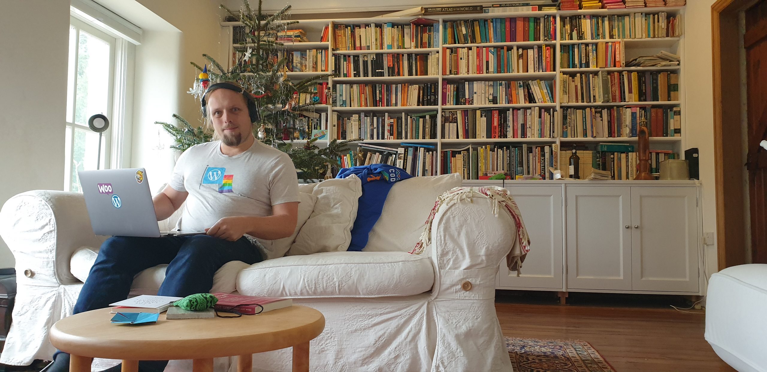 Full image of Dan working on a MacBook covered with Automattic stickers, wearing a WordPress Diversity t-shirt.