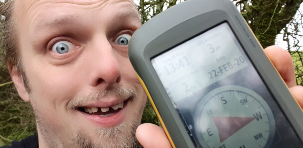 Dan grinning holding a GPSr showing that he's at the hashpoint
