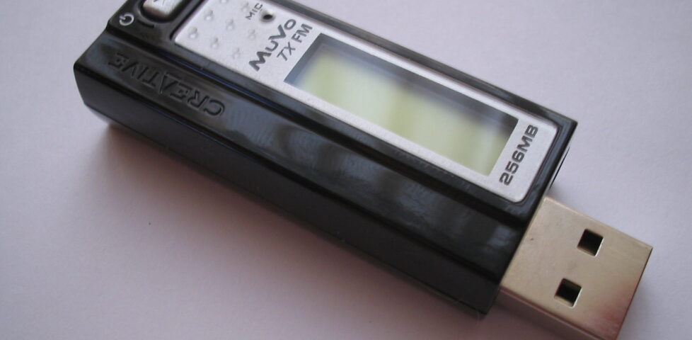 A Creative MuVo MP3 player (and FM radio), powered off, on a white surface.