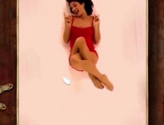 A woman lies on a bed with her legs crossed, playfully wagging her finger. The mouse cursor is shaped like a feather.