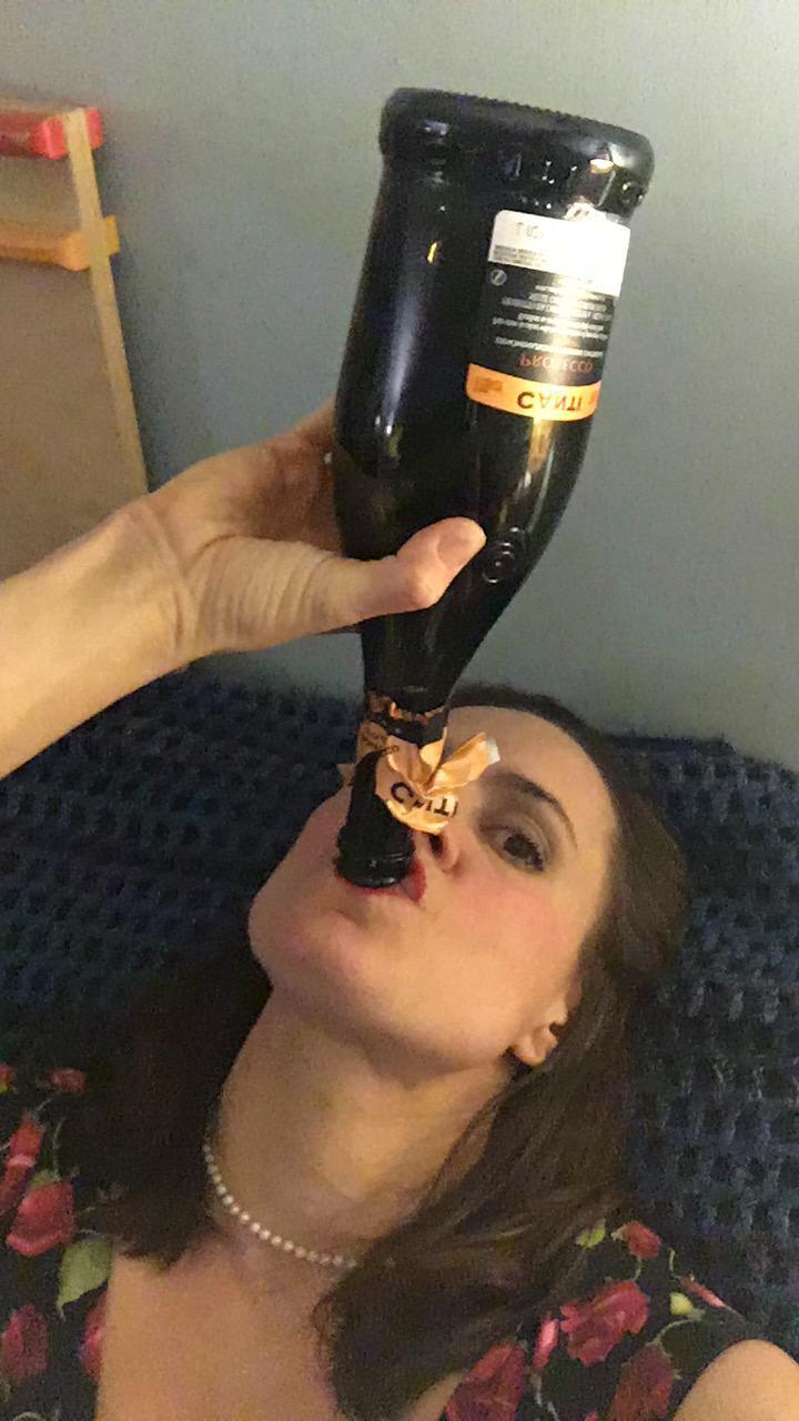 Full image of Jen drinking from the neck of a nearly-empty wine bottle.