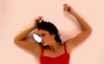 A woman blows a feather away from her face.