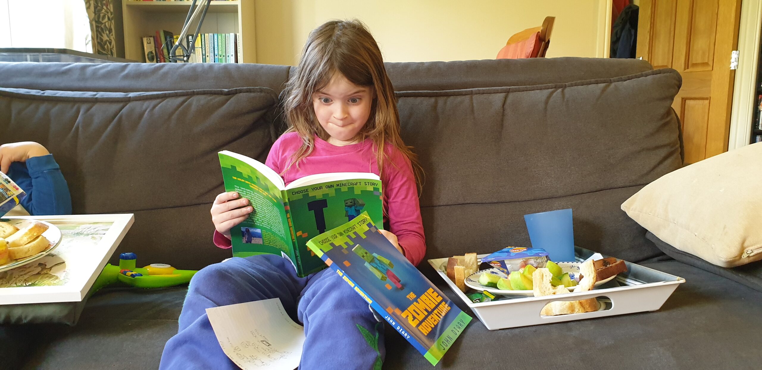 Full image of Annabe enjoying Choose Your Own (Minecraft) Story books.