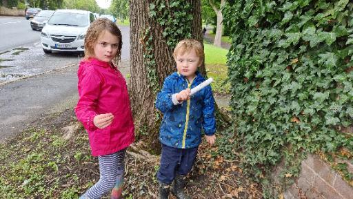 Annabel and John holding a tube-shaped cache container.