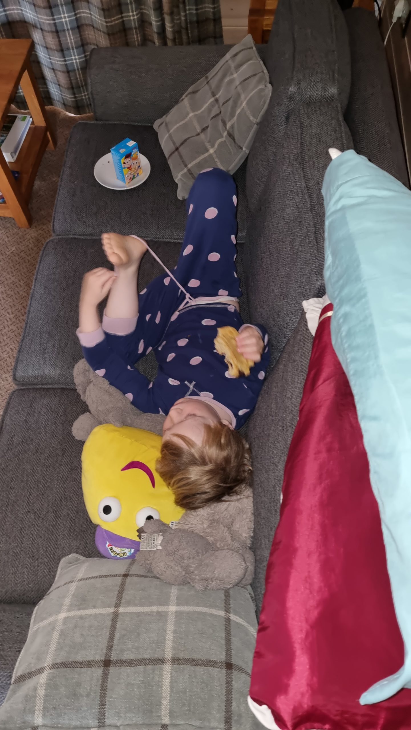 Full image of Lounging on the sofa with a CBeebie toy.