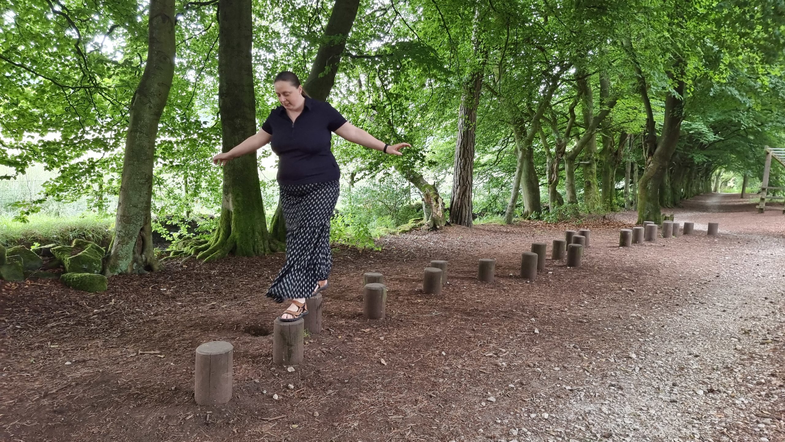 Full image of Ruth hops across balancing logs in the Darwin Forest.