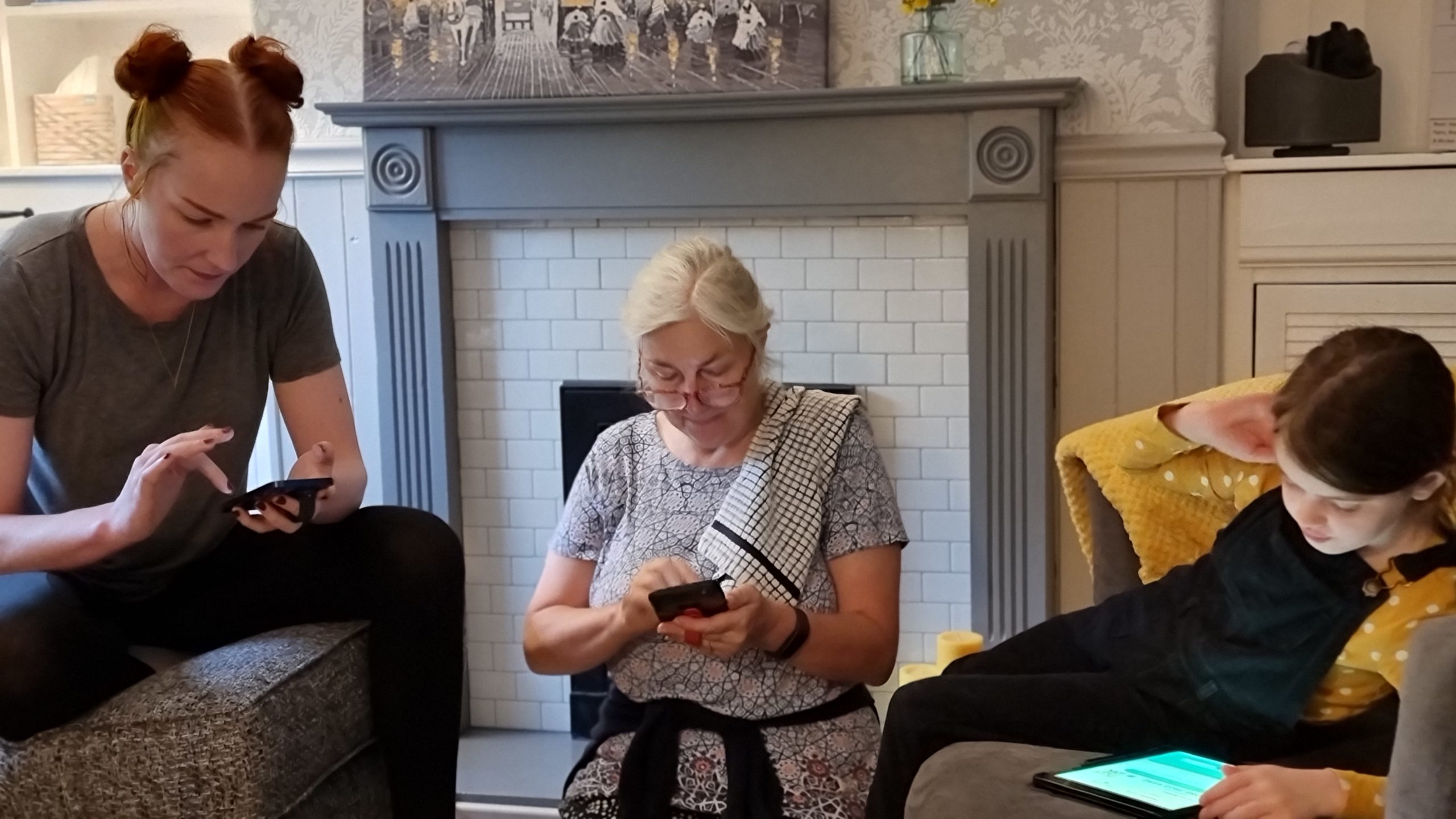 Full image of Two adults and a child using mobile phones and tablets.