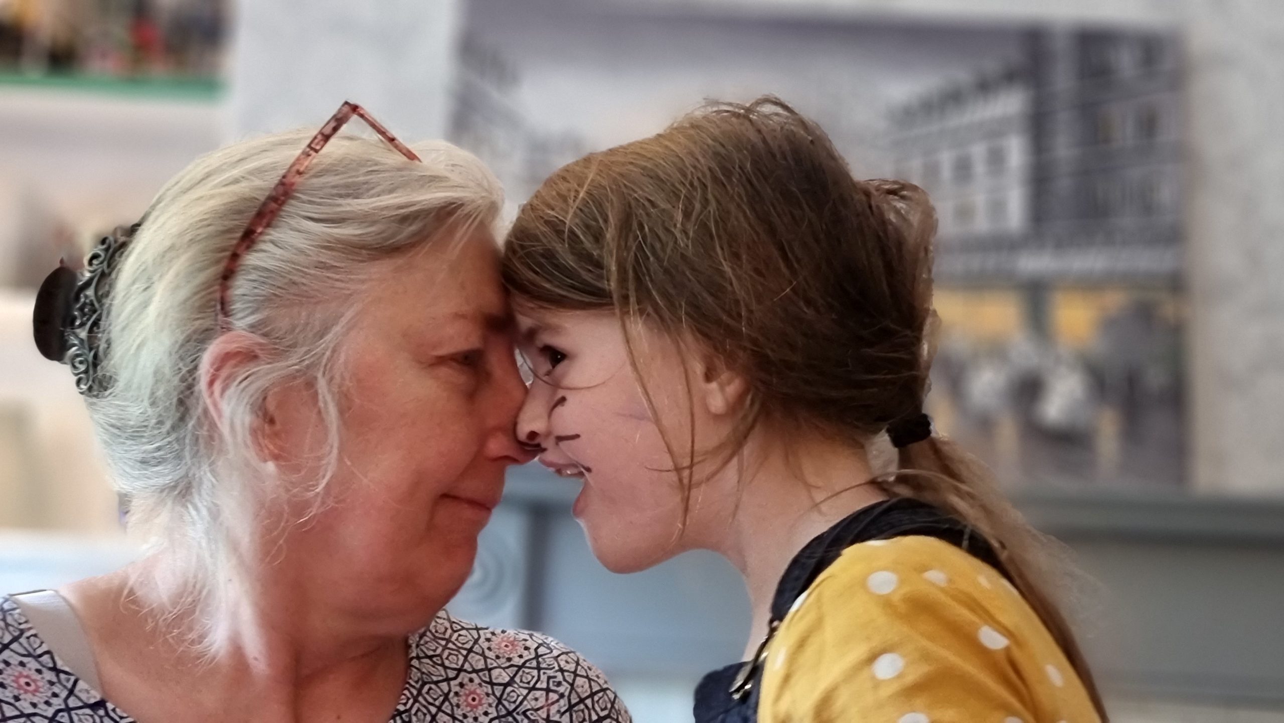 Full image of A woman and a girl press their faces together and rub noses.