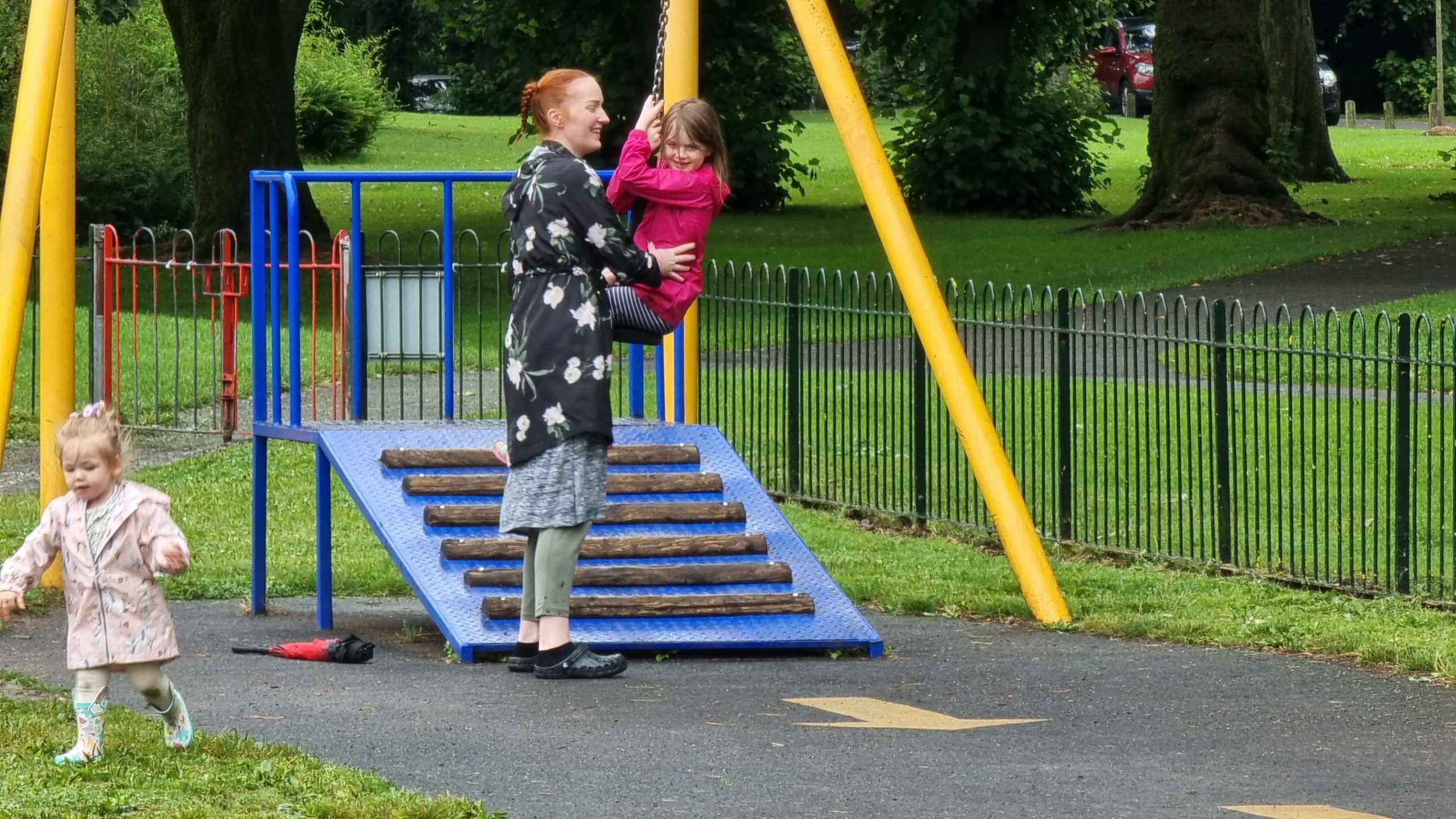 Full image of Sarah helps a child on a zipline.
