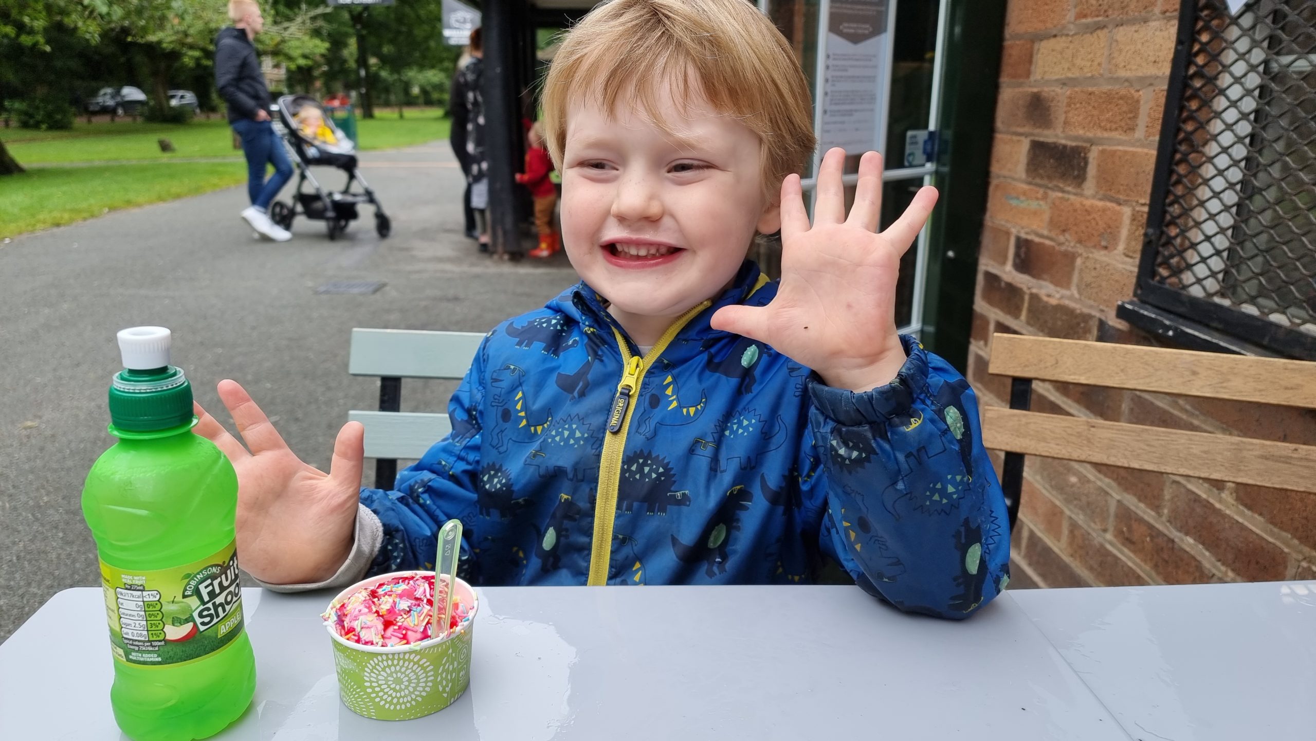Full image of A boy enjoys an ice cream at a park cafe.