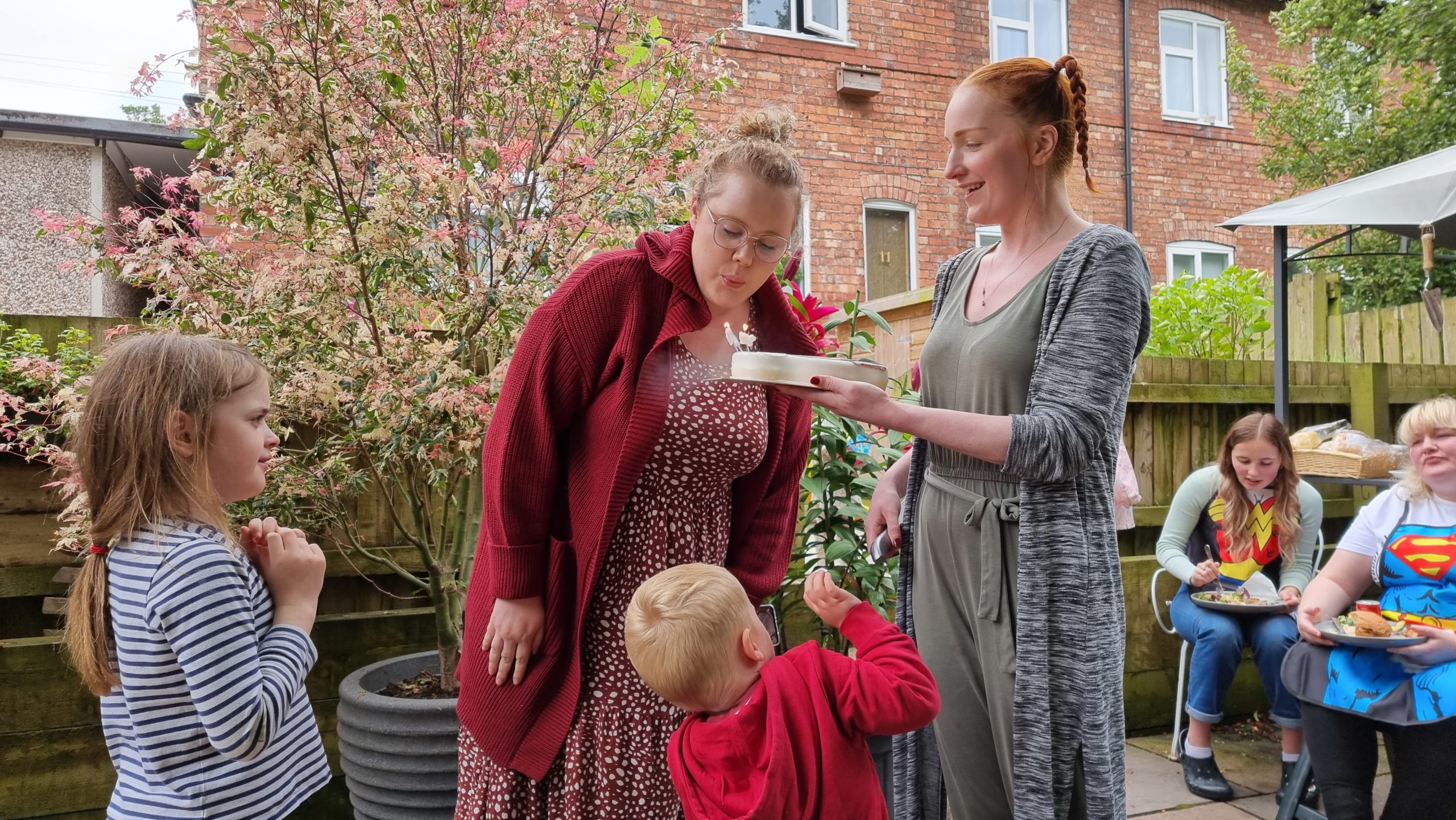 Full image of Jemma blows out candles on a birthday cake.