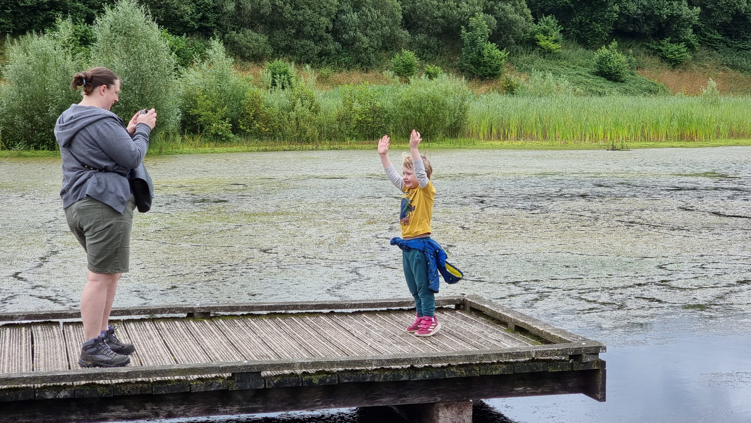 Full image of Ruth photographs her 4-year-old as he stands on a pontoon dock.
