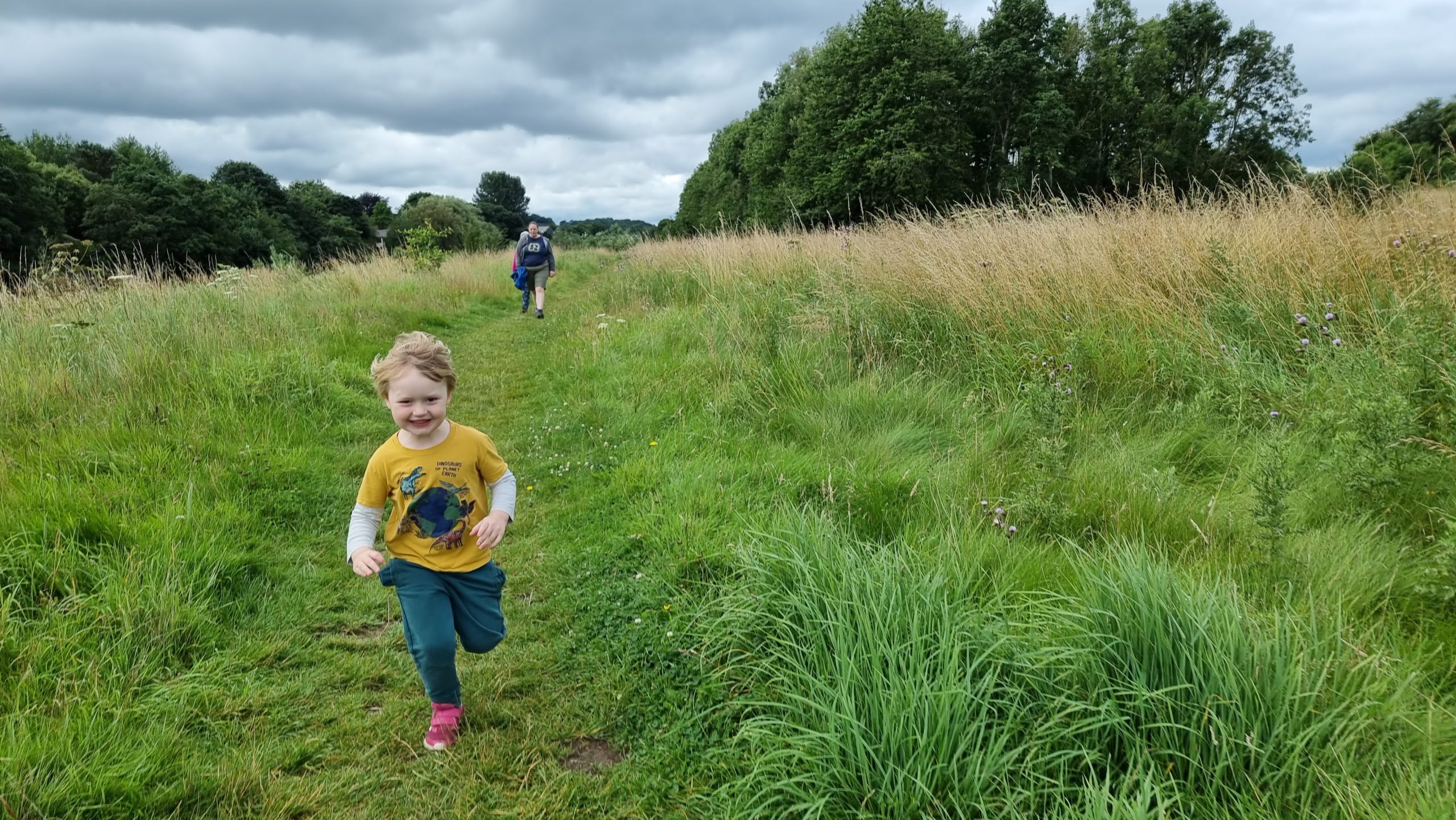 Full image of A boy runs away from two adults.