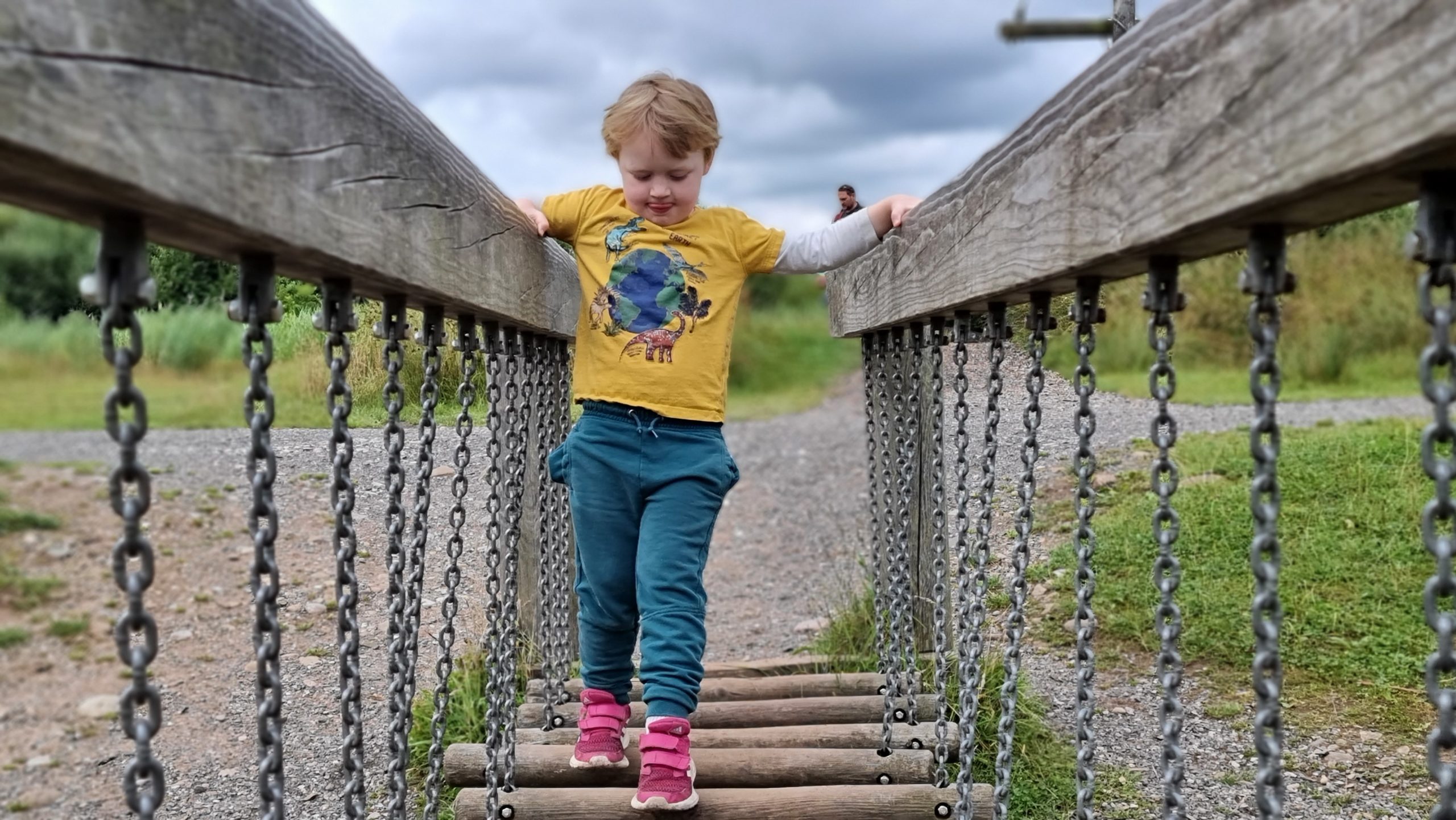 Full image of A boy concentrates hard as he crosses a wobbly bridge.