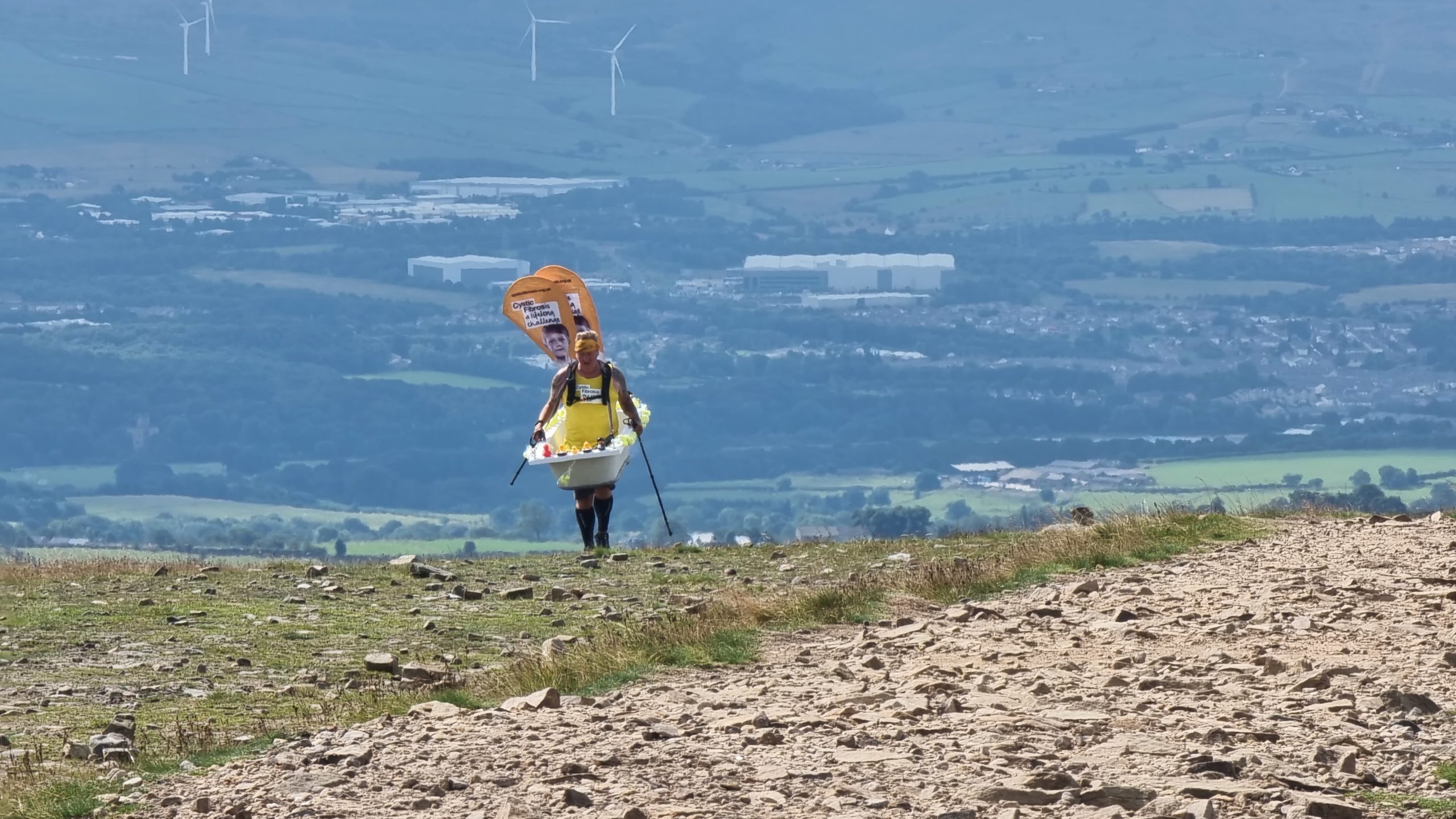 Full image of Steve Taylor wearing a bathtub and climbing Pendle Hill.