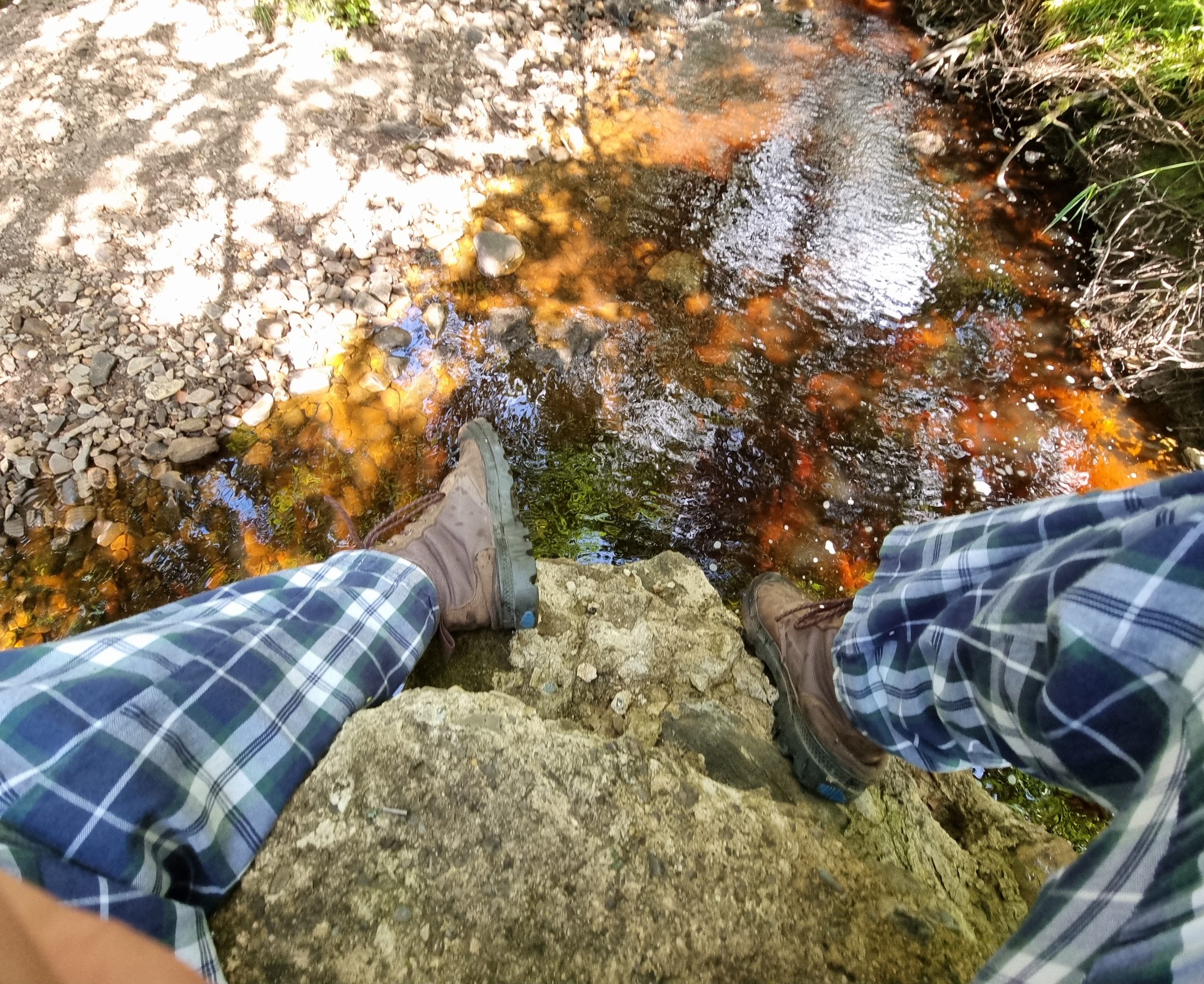 Full image of Orange-red river water beneath Dan's feet.