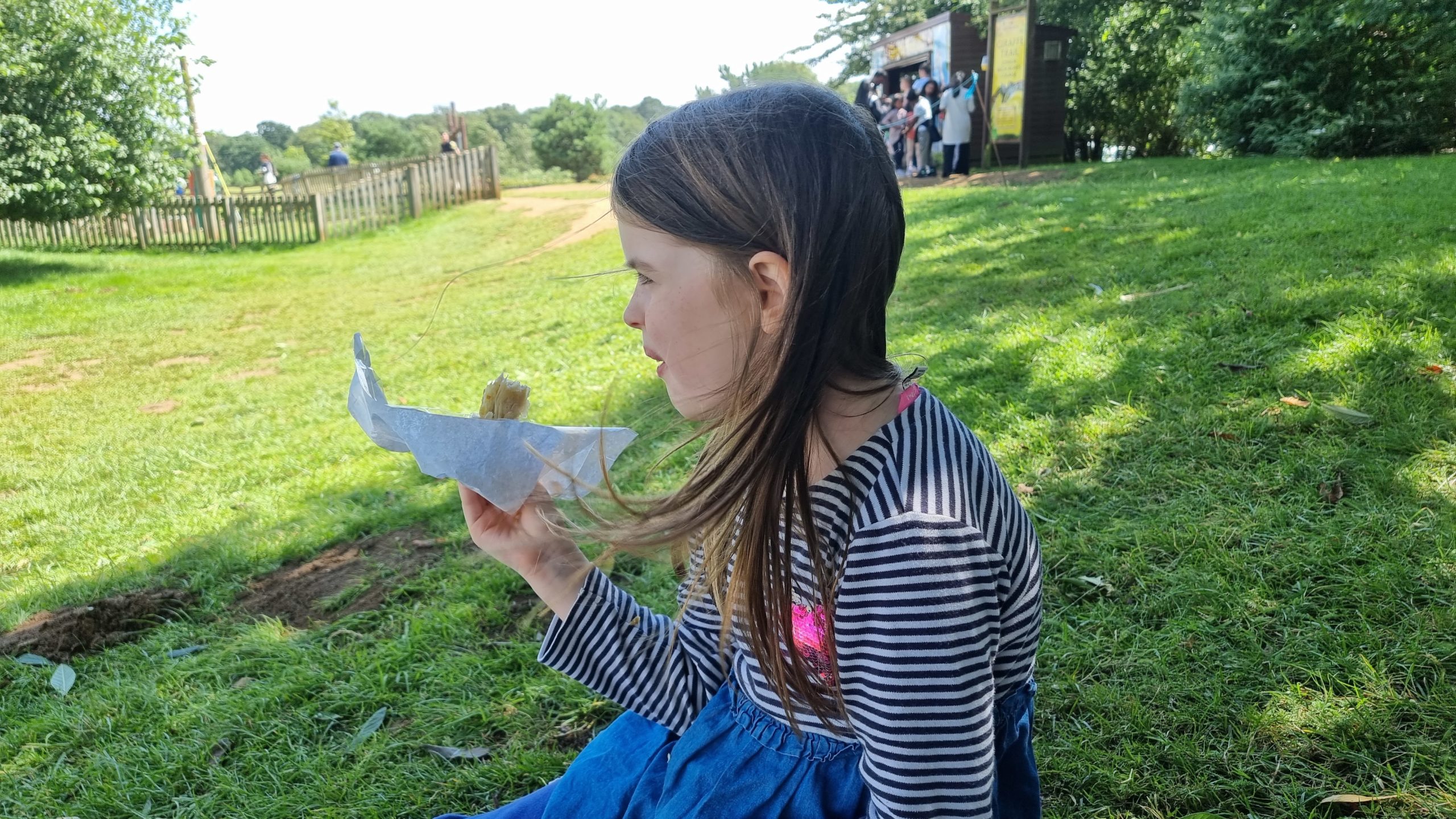 Full image of Girl eats half a sausage roll.