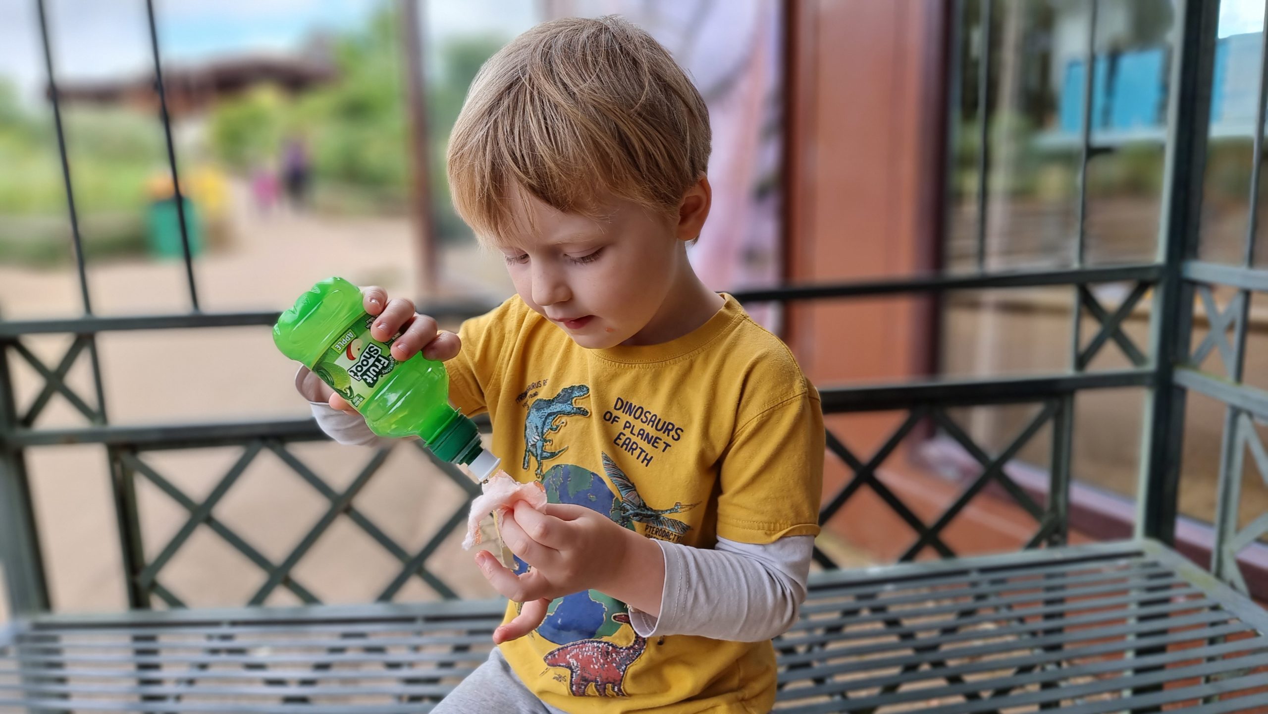 Full image of A boy pours a juice drink onto some candy floss.