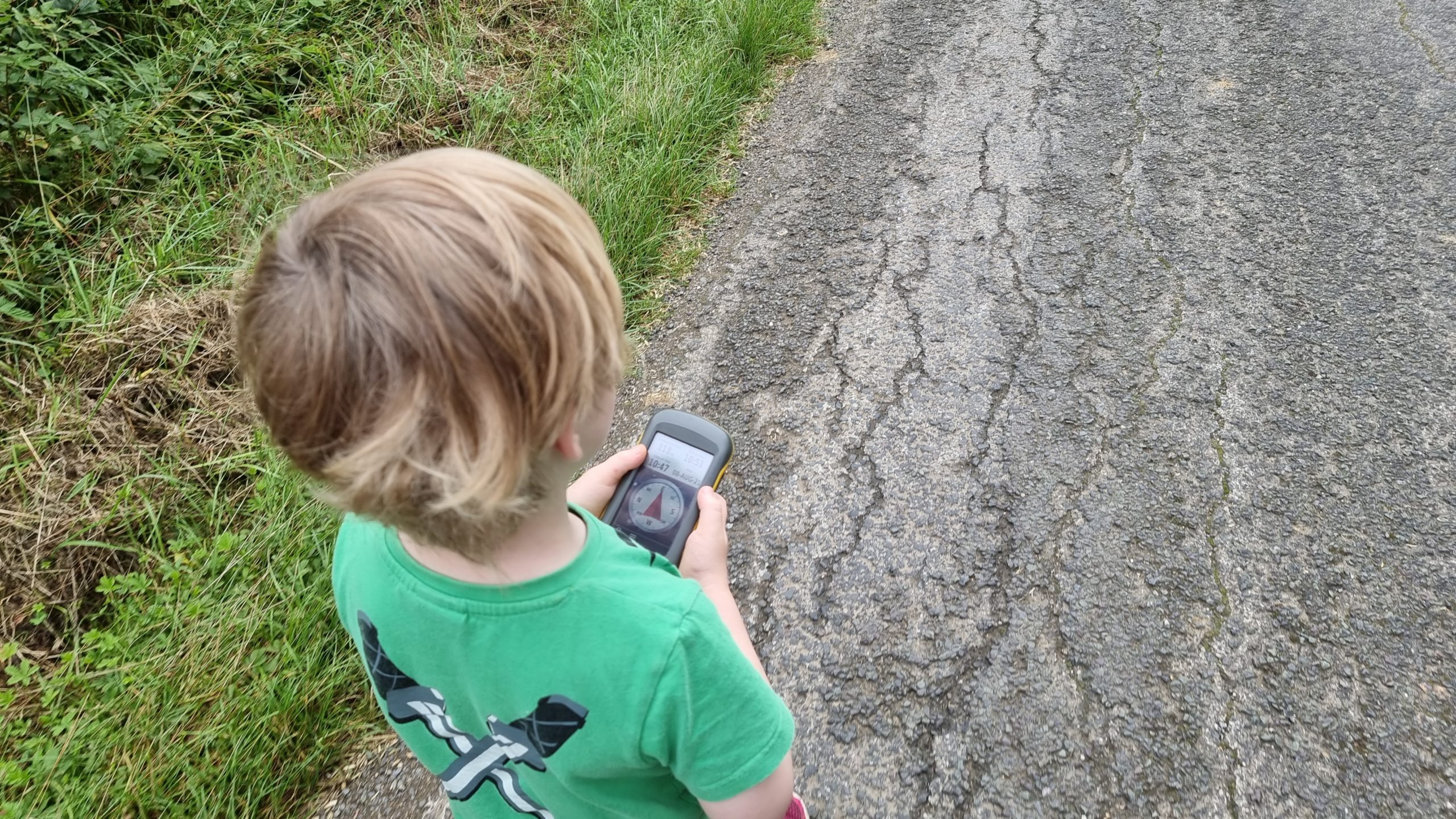 Full image of A boy holds a GPS receiver as he walks down a lane.