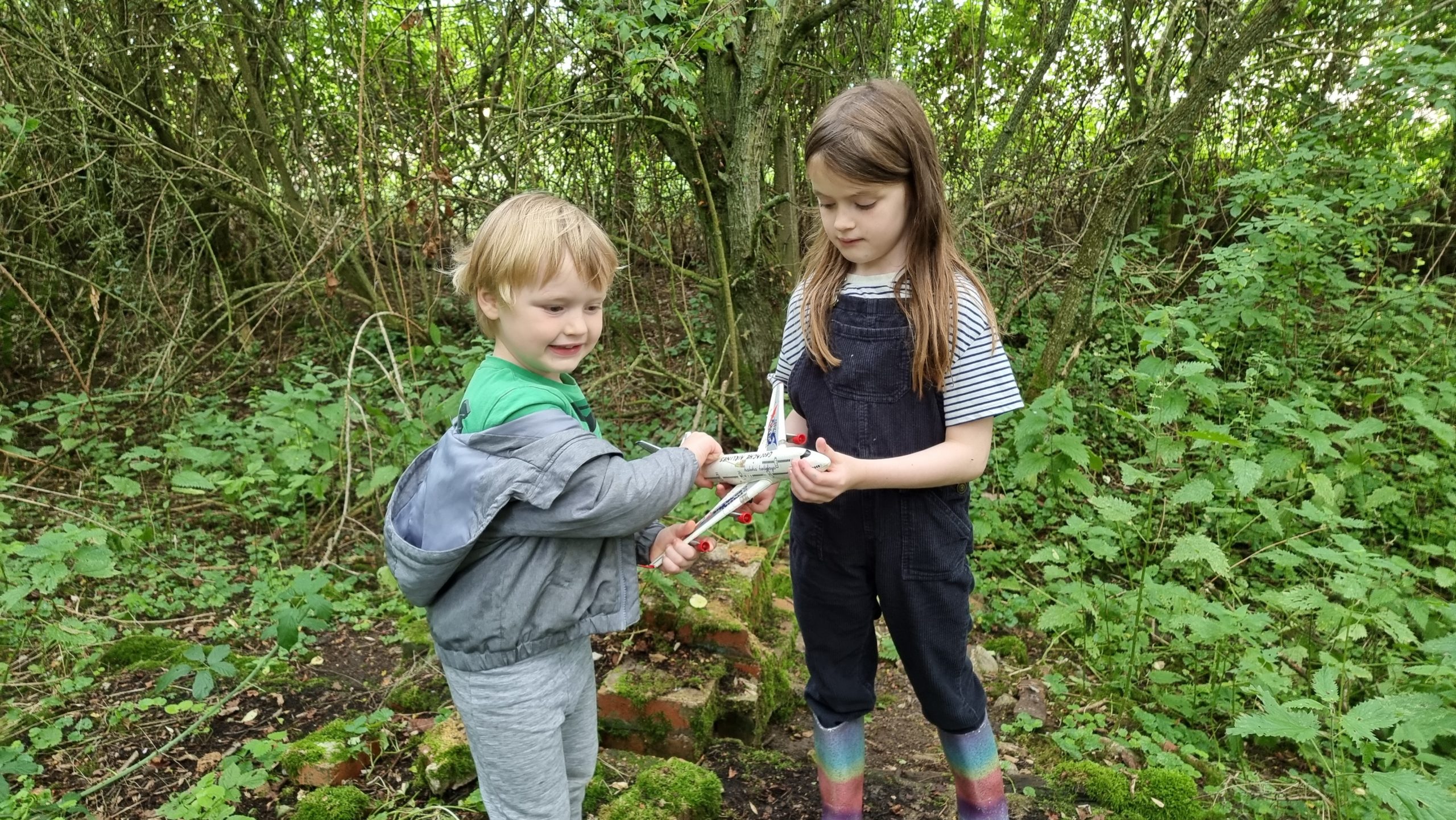 Full image of Children hold a toy plane with "geocache airlines" written on it.
