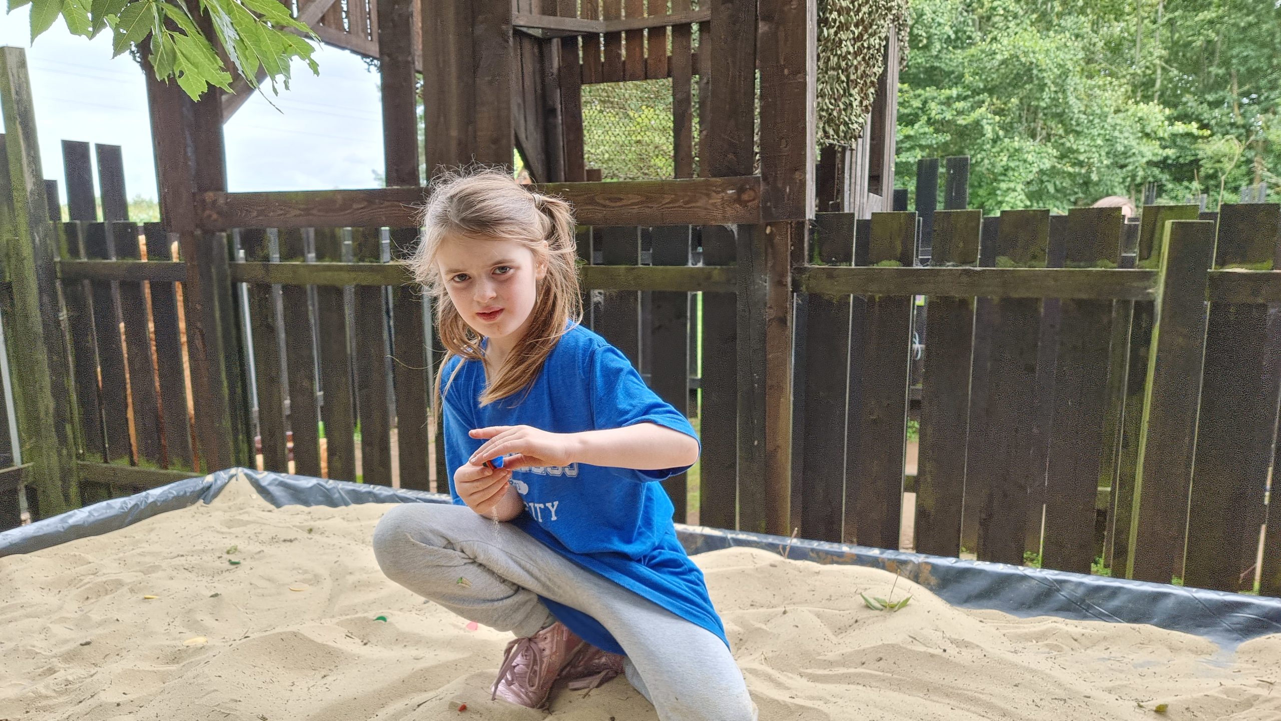 Full image of A girl digs in a tabletop sandpit.