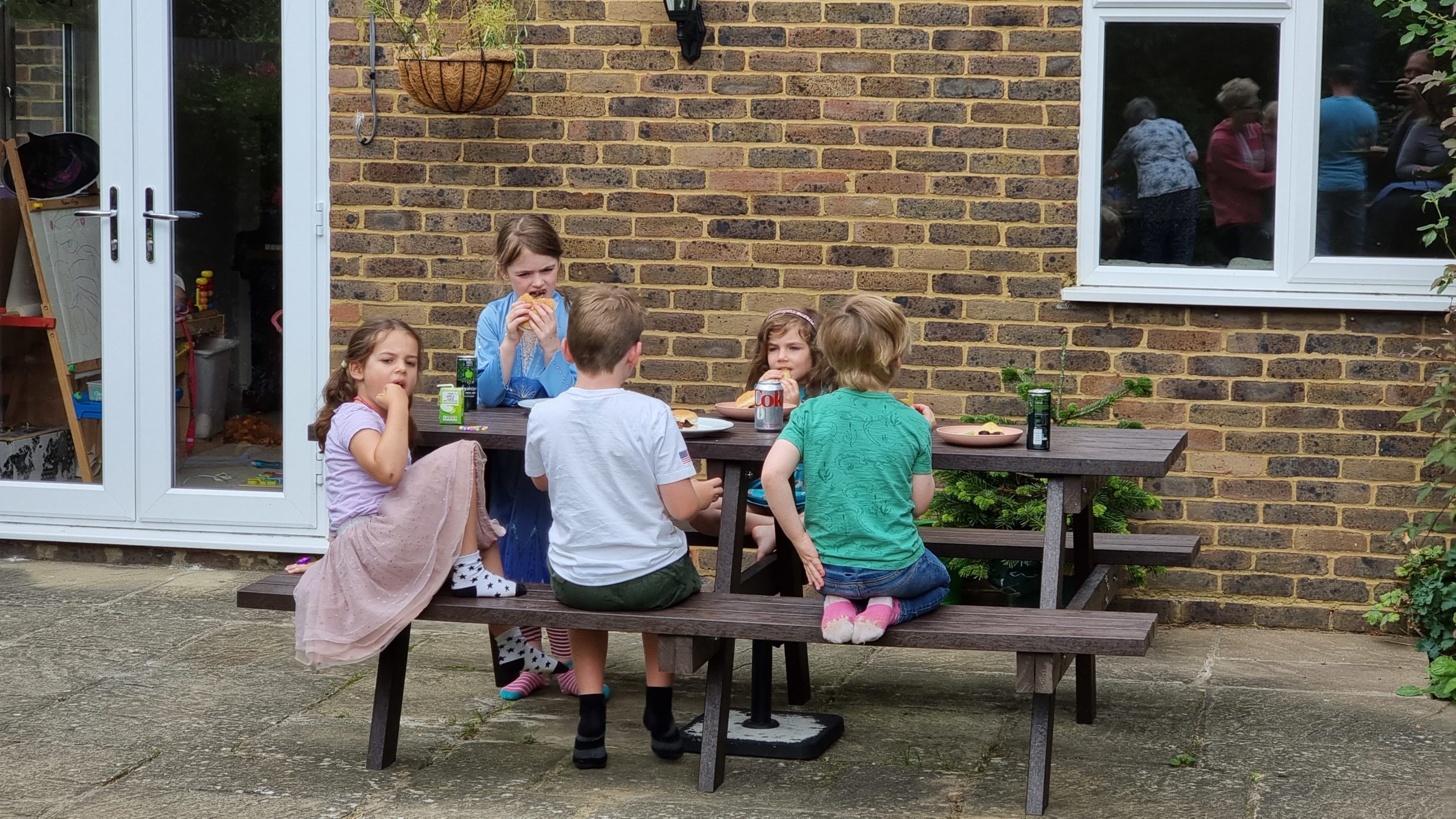 Full image of Children at a picnic table in a garden.