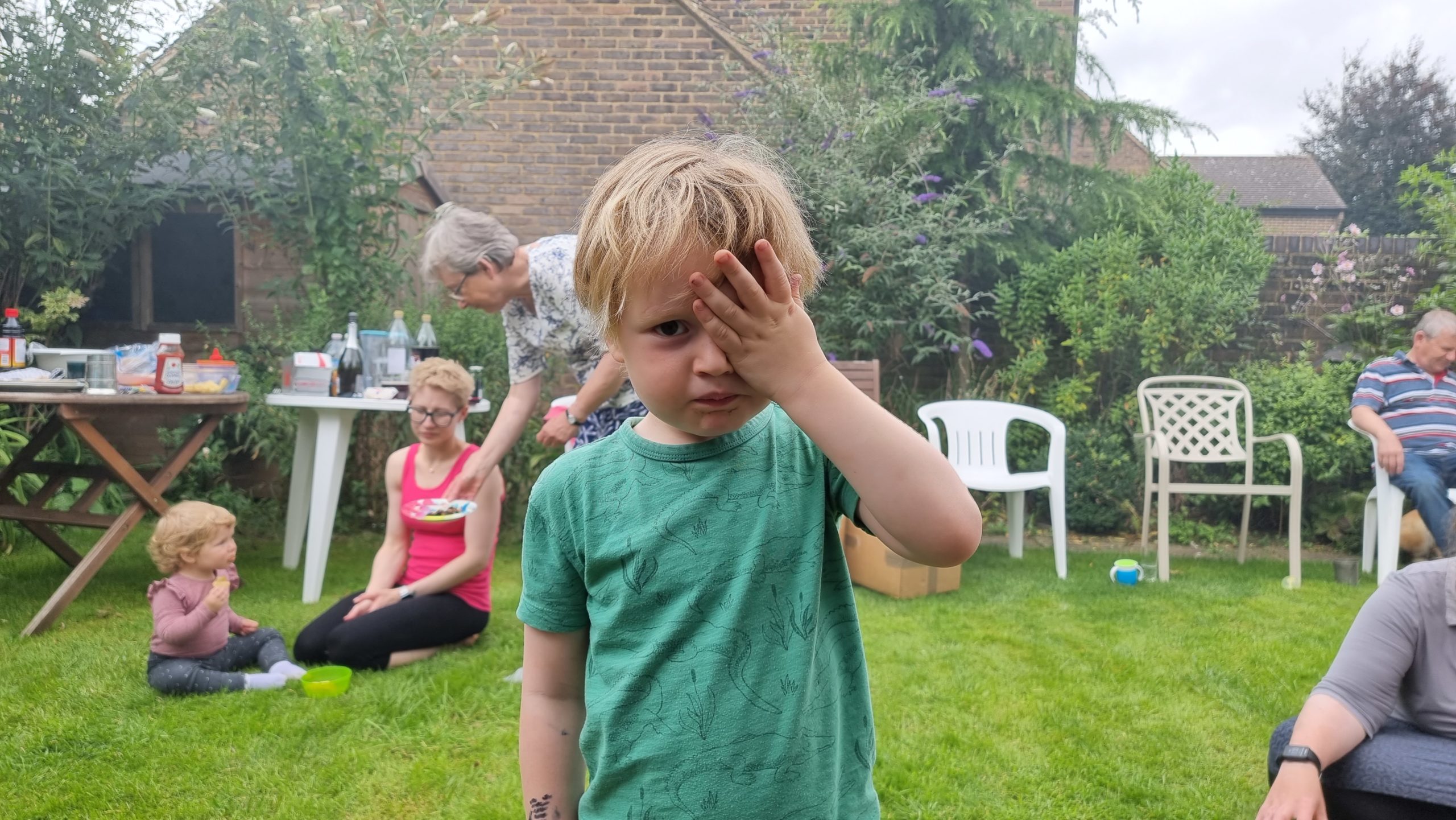 Full image of A child in the smoke of a barbecue holds his hand over his eyes.