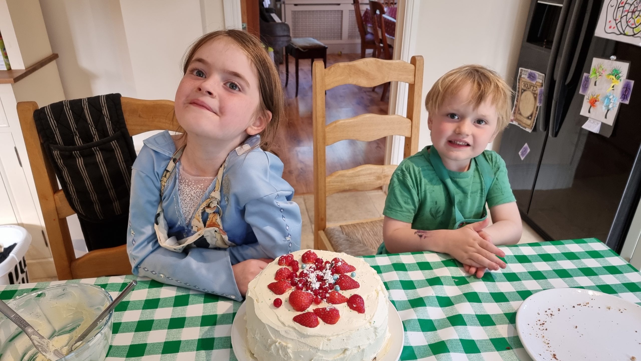 Full image of The kids pose with a fruit-topped cake.