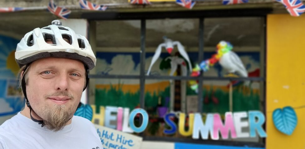 Dan outside a disused bus stop repurposed as a "beach hut".