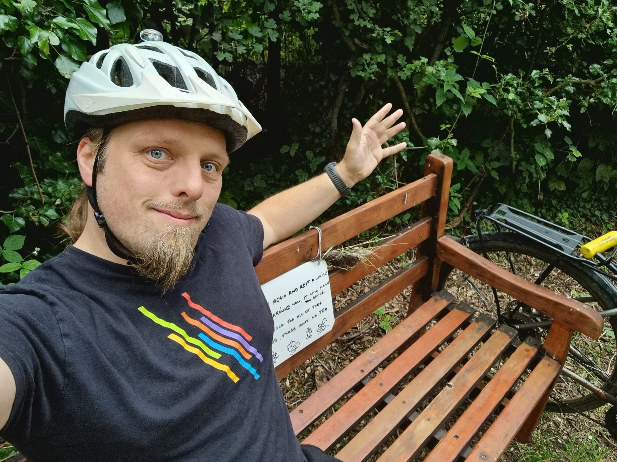 Full image of Dan wearing a cycle helmet sitting on a wooden bench.