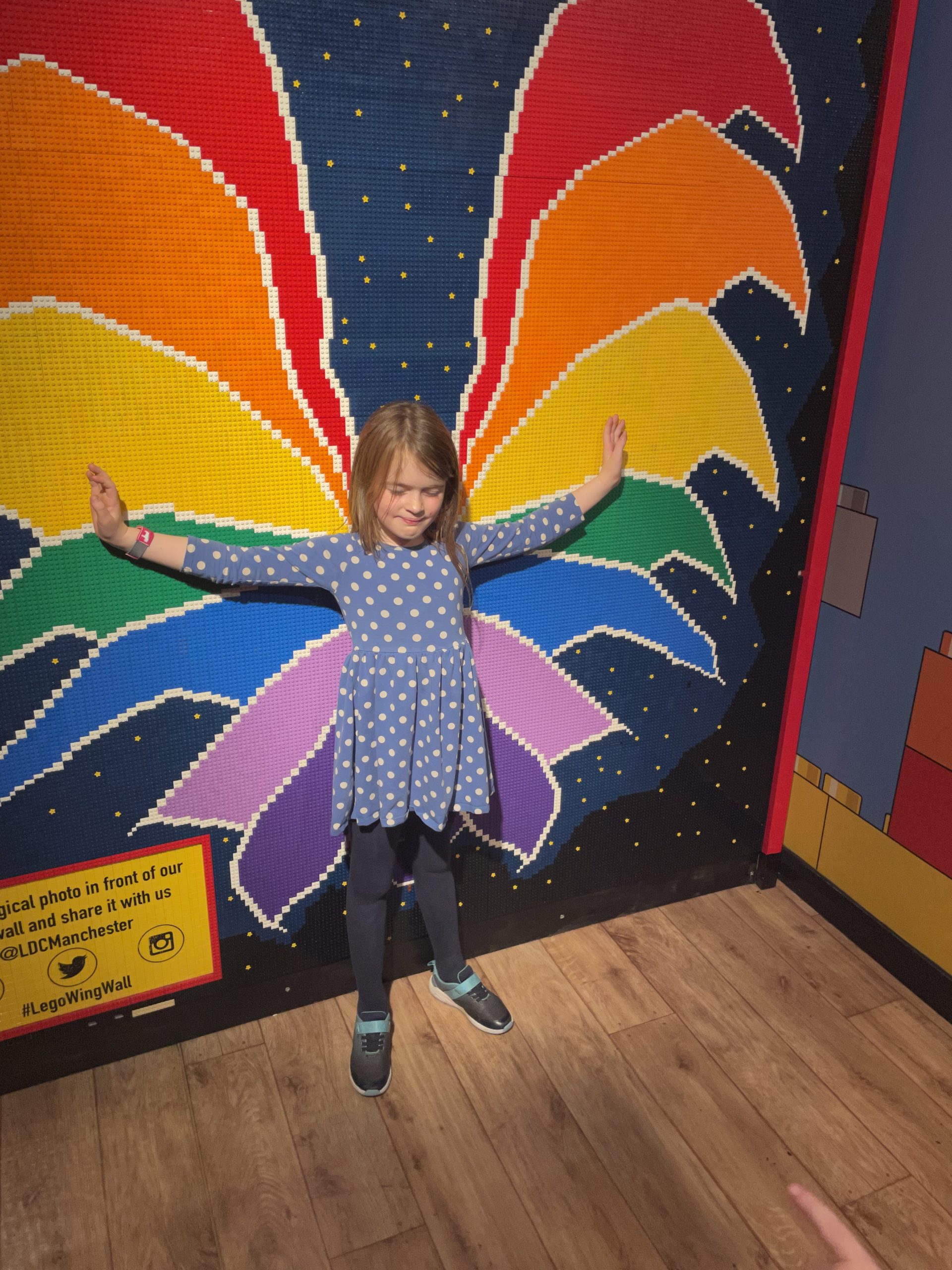 Full image of Girl in front of a LEGO mosaic of butterfly wings.