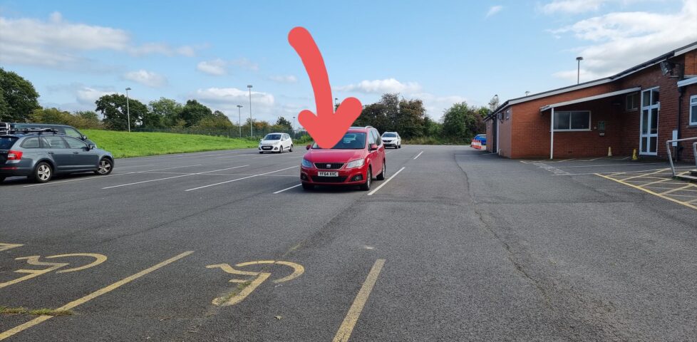 Car in car park with a large arrow pointing at it.
