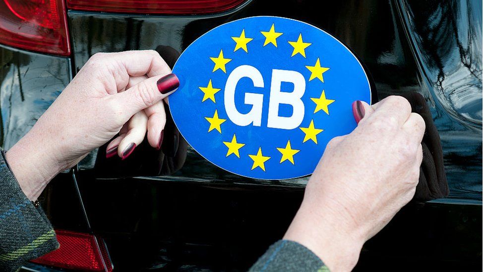 GB sticker being affixed to a car.