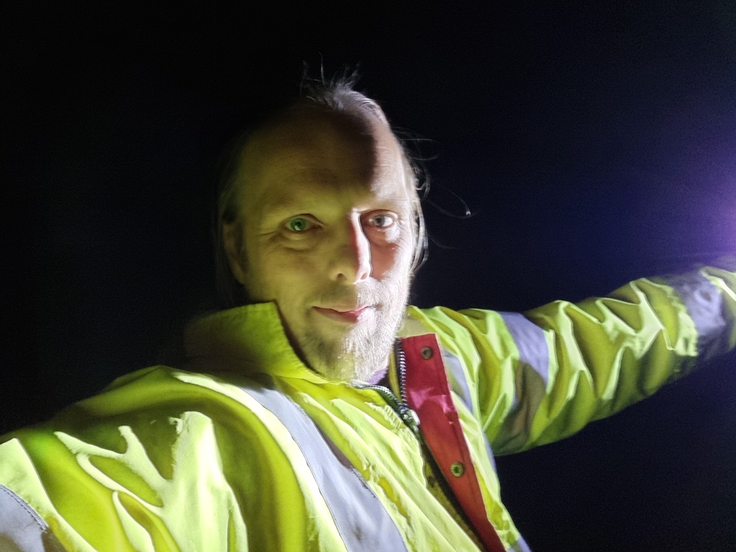Full image of Dan, in the dark, lit only by a torch.