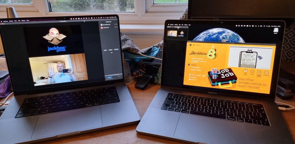 Two laptops: one showing a full-screen Zoom chat with Dan and "Jackbox Games"; the second showing a windowed copy of Jackbox Party Pack 8.