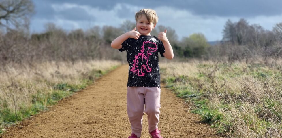 Five year old boy on a footpath with two thumbs up.