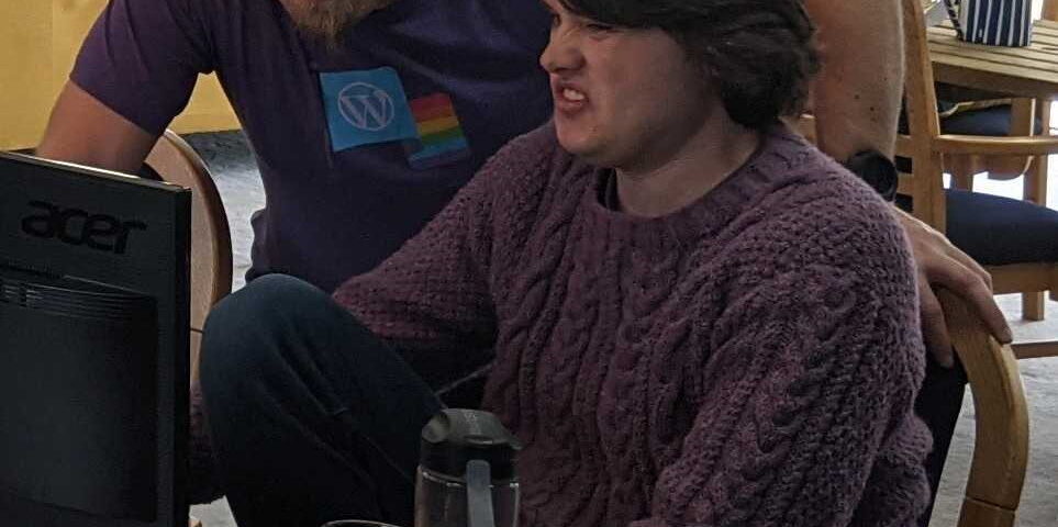Dan and Jacob look at a piece of code together; Dan is smiling but Jacob looks disgusted.