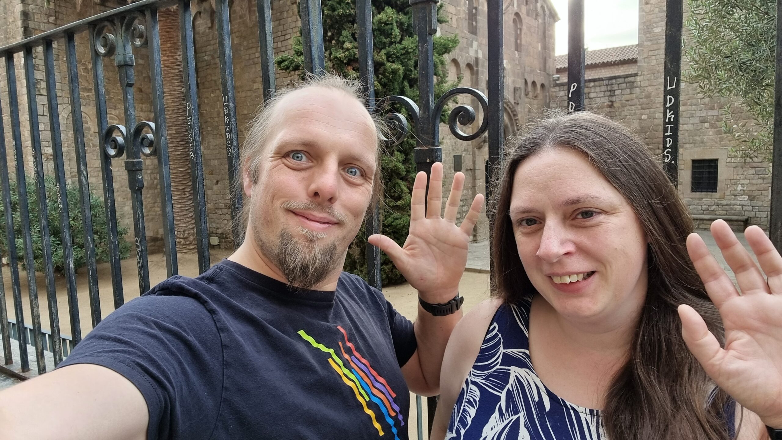 Full image of Dan and Ruth in front of a monastary gates, smiling and waving.