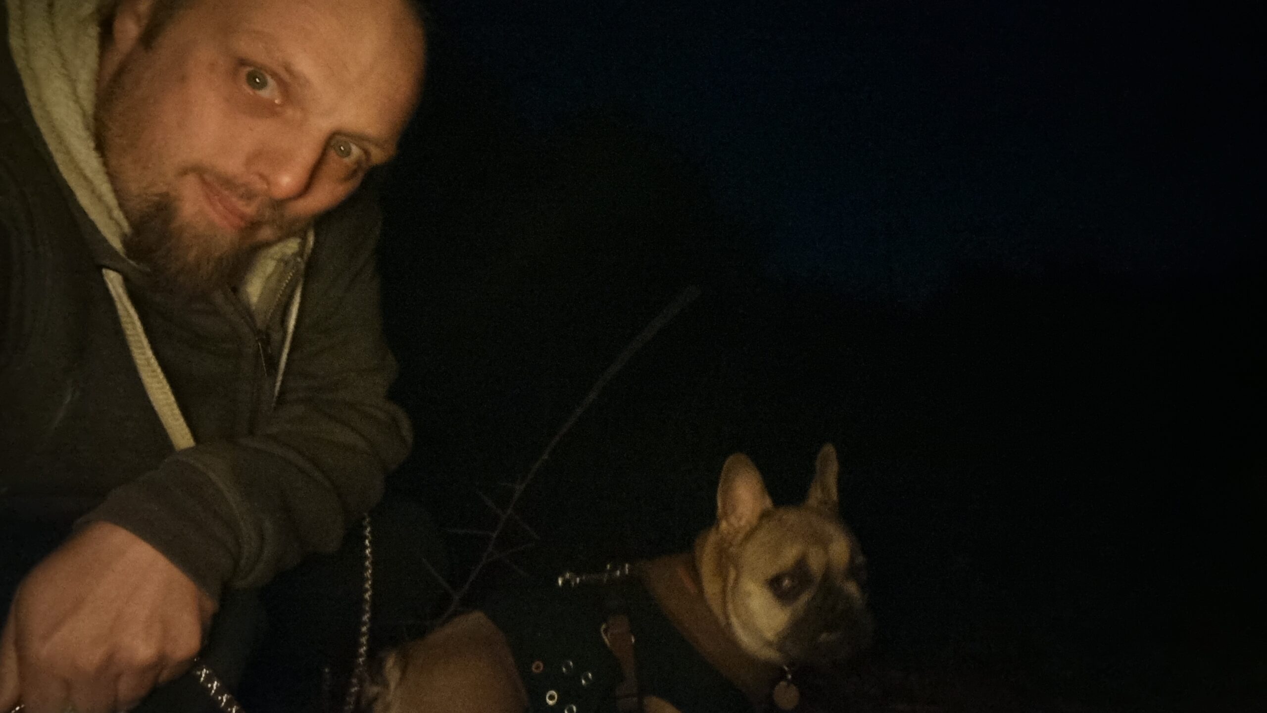 Full image of Dan takes a selfie in the dark; a French Bulldog looks confused in the background.