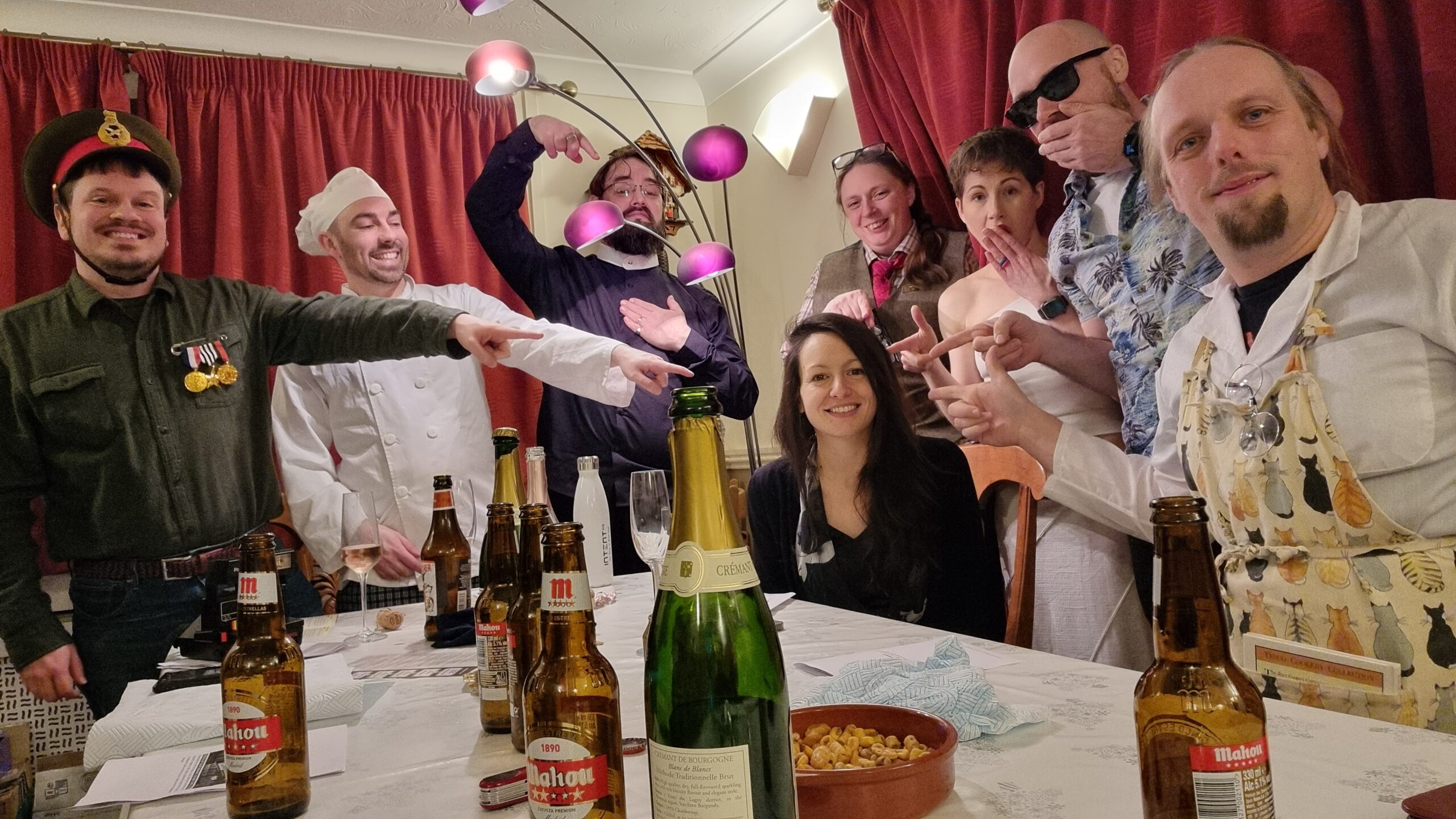 Full image of A party of unlikely characters stands around and points accusingly at the "murderer" among them: it's Kirsty.