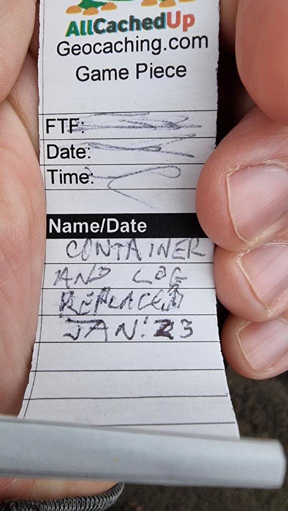 Fresh geocaching log book with a message stating that it's a replacement, added January 2023, held in a hand.