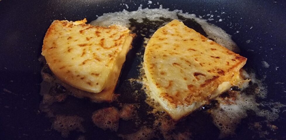 A pair of tattie scone quesadillas sizzling in a pan.