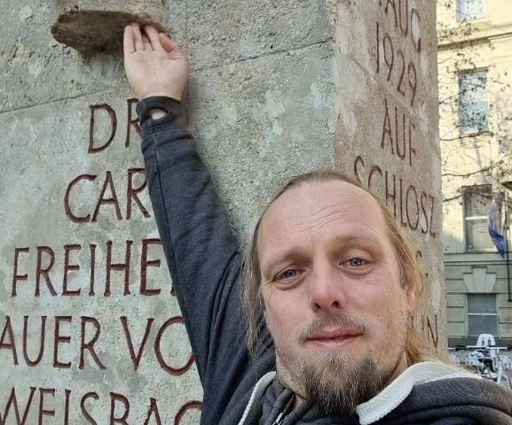 Dan reaches up to touch a bust of Dr. Carl Auer, Freiherr von Welsbach, Austrian chemist and engineer.