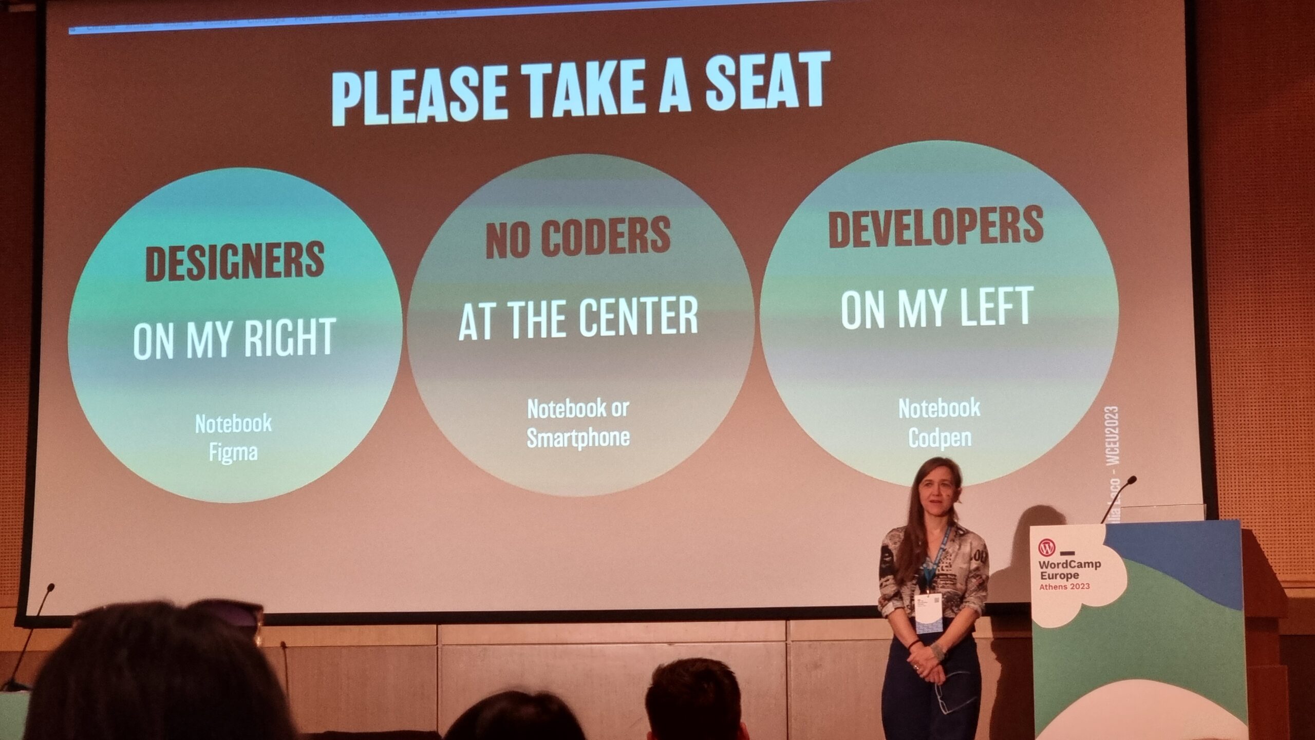 Full image of A title slide encourages designers to sit on the left (to the right of the speaker), developers to the right (on her left), and "no-coders" in the centre.