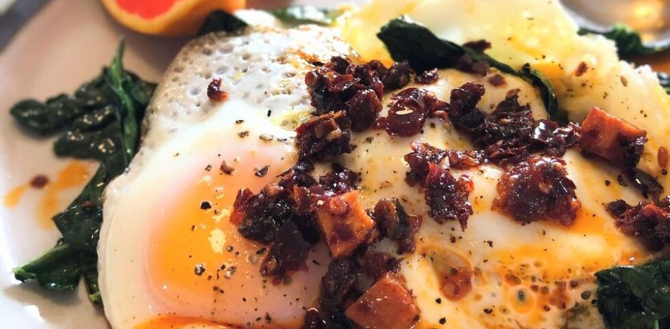 A plate of fried eggs with chilli flakes on a bed of kale.