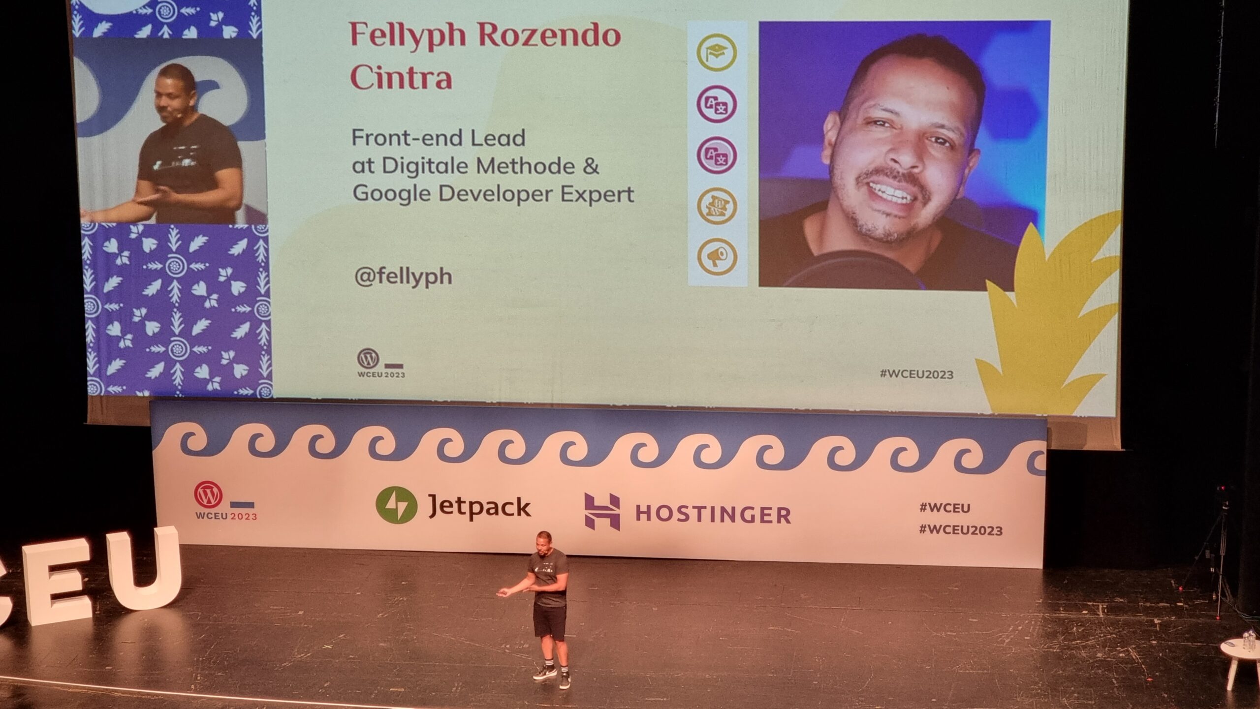 Full image of Fellyph Cintra stands in front of a large screen showing a slide that introduces himself to his audience: "Front-end Lead at Digitale Methode & Google Developer Expert @fellyph"