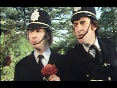 Framegrab from first and only episode of 1974 TV sketch comedy show Out of the Trees, showing two uniformed policemen, one of them holding a crimson peony.