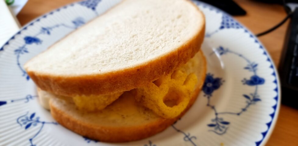 Thich white sandwich on a blue-and-white china plate, with the distinctive shape of an organge-coloured Monster Munch crisp poking out.